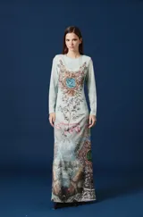 Vestido largo de corte recto y manga larga, con cuello redondo. Presenta un estampado artístico integral con motivos botánicos, paisajes montañosos y fauna, en tonos celestes, marrones y verdes.