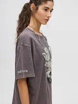Remerón oversize de algodón, corte cuadrado y básico, color gris oscuro con efecto gastado. Estampa frontal de una figura abstracta o mano en tonos claros y texto en un idioma asiático en la manga.