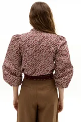 Pantalón culotte color camel con sutiles rayas bordó, de cintura alta y reforzada, con pinzas en la cintura, cierre frontal con gancho y botón interno, y bolsillos laterales. Las piernas son anchas.