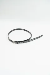 Cinturón fino de cuero sintético color celeste, con perforaciones metálicas a lo largo de toda la tira y hebilla metálica plateada.