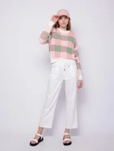 Sweater de tejido de punto con diseño jaquard a cuadros en tonos rosa y verde. Es de manga larga y cuello a la base.