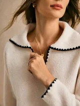 Sweater de punto color off white con cuello estilo sailor y detalles de borde festoneado en contraste negro en cuello, puños y ruedo. Presenta un diseño de manga larga y calce relajado.