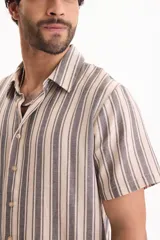 Camisa de manga corta de tejido jacquard con estampado de rayas verticales en tonos beige y gris. Presenta cuello camisero clásico y cierre frontal de botones.