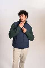 Chaleco puffer de color azul marino, con cierre frontal completo y cuello alto. Presenta un diseño acolchado horizontal y el logo de la marca bordado en el pecho.