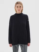 Buzo tejido de punto color negro, con cuello subido tipo polera, diseño oversized y largo con pequeños tajos laterales.