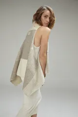 Chaleco sin mangas de lana fina sin teñir, color crudo, con cuello volcado y diseño a cuadros sutil. Presenta terminación a mano en crochet.