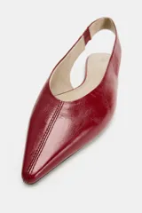 Zapato plano destalonado en piel de color rojo, con diseño de punta fina y detalle de costura central en la parte delantera. Cuenta con tira trasera y suela baja.