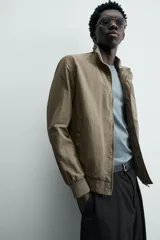 Cazadora azul marino de corte regular fit, confeccionada en tejido técnico repelente al agua. Presenta cuello subido, manga larga, bolsillos de vivo en cadera, bolsillo interior y acabados en rib en puños y bajo. Cierre frontal de cremallera oculta por solapa con botones a presión.