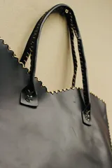 Cartera de cuero color marrón chocolate con manijas largas y borde superior en corte en V. Diseño amplio y liviano, con terminaciones artesanales y costuras contrastantes en todo el contorno.