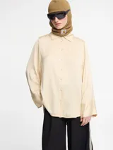 Camisa color crema con botones en la parte delantera y mangas largas.