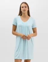 Camisón corto de corte evasé celeste con estampado geométrico, mangas cortas y amplio escote redondo. Presenta detalle de puntilla calada en el contorno del cuello con pequeño moño decorativo en el centro y fruncidos frontales.