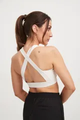 Top deportivo blanco con tiras cruzadas en la espalda y elástico en la cintura.