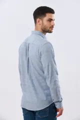Camisa de manga larga confeccionada en mezcla de lino y algodón, con sutiles rayas celestes, cuello camisero clásico y cierre frontal de botones.