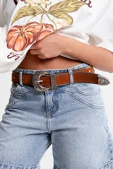 Cinto marrón de cuero gamuzado con hebilla, pasador y puntera metálicos con diseño floral.