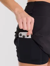 Falda deportiva negra con calza interior y bolsillo lateral. Diseño cruzado en la parte frontal.