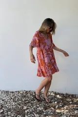Vestido corto con volados, estampado con hojas en tonos rosa y naranja, de corte suelto y mangas cortas.