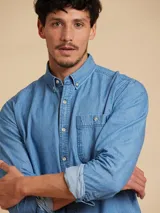 Camisa celeste de manga larga con cuello abotonado y bolsillo en el pecho.