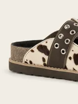 Zueco de cuero vacuno con estampado animal print tipo vaca, con hebilla decorativa metálica con ojales y suela de corcho con vira reforzada.