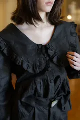 Camisa de lino con cuello grande con volados, mangas largas abullonadas con puños y cierre frontal con botones forrados.