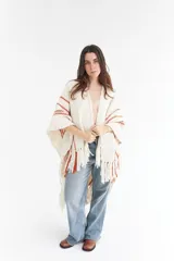 Ruana artesanal color crudo con rayas horizontales color ladrillo y flecos.