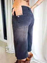 Bermuda de jean negro con efecto lavado, corte recto y largo por debajo de la rodilla. Cuenta con bolsillos traseros y etiqueta decorativa en uno de ellos.