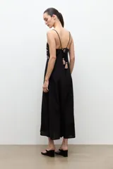 Maxi vestido largo de color negro, de corte recto y tirantes finos. Presenta un diseño bordado multicolor en la zona del pecho con motivos geométricos y florales.