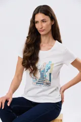 Remera blanca de manga corta y cuello redondo, con estampa frontal ilustrativa de un paisaje urbano con escalinatas en tonos azules y tierra.