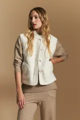 Chaleco de paño color marrón oscuro, de silueta recta y diseño minimalista. Presenta cuello a la base, cierre frontal con botones claros y bolsillos aplicados.