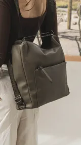 Cartera convertible en mochila de diseño versátil, color tostado, con textura granulada. Cuenta con un bolsillo frontal con cierre, compartimento principal espacioso y correas ajustables para llevar al hombro o como mochila.