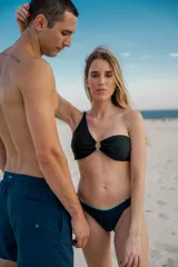 Top de bikini negro con textura, un solo tirante y aro metálico dorado en el centro.