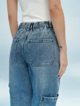 Pantalón jean de corte relaxed, con diseño cargo, cintura elástica con cordón ajustable y puños elastizados en los tobillos. Presenta bolsillos laterales en las piernas y bolsillos traseros.