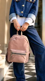 Mochila de nailon color rosado, con bolsillo frontal con cierre y detalles en símil cuero. Cuenta con amplia capacidad interior, asas de mano, correas regulables y un bolsillo trasero vertical.