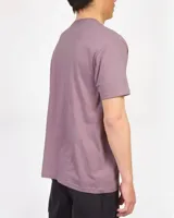 Remera lila de manga corta con cuello redondo y estampa frontal de estilo gráfico y texto en tonos amarillos y negros.