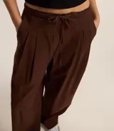 Pantalón wide leg de estilo sastre color marrón, con cintura elástica, lazo ajustable y pliegues frontales. Presenta un corte recto y fluido.