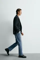 Jeans de mezclilla rígida de algodón, color azul claro con efecto lavado y ligero desgaste. De tiro medio, corte recto desde la cadera hasta la rodilla y ligeramente acampanado en el bajo (bootcut). Cierre frontal con botonadura y cinco bolsillos.