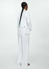 Chaqueta vaquera de corte corto en color blanco, con cuello de solapa, manga larga con puños abotonados, cierre frontal de botones metálicos, bolsillos de parche con solapa en el pecho y bolsillos laterales ribeteados.