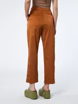 Pantalón de gabardina color marrón óxido, de corte recto, con pinzas dobles en la cintura, bolsillos laterales y cierre con botón y cremallera.