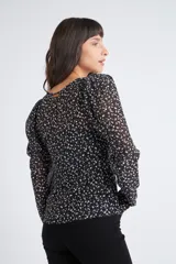 Blusa rosa con estampado de flores blancas y amarillas, cuello en V, manga larga abullonada y cierre frontal con botones.