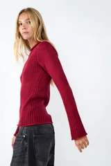 Sweater de punto color rojo con cuello redondo y mangas largas levemente acampanadas. Presenta diseño de rayas en contraste y ruedo recto.