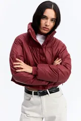 Campera puffer de corte cropped, color marrón oscuro, con cuello alto, cierre frontal con cremallera y botones a presión, y puños elásticos.