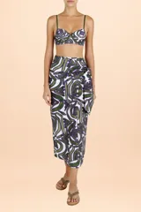 Pareo largo de diseño envolvente con nudo lateral, confeccionado en tejido fresco con estampado de motivos orgánicos en tonos verde y violeta sobre fondo blanco.