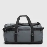 Bolso tipo duffel de diseño versátil, color gris con detalles en negro. Cuenta con un compartimento principal amplio, bolsillos exteriores con cierre, asas de mano y correas ajustables para llevar como mochila.