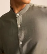 Camisa de manga corta, corte slim, color verde oliva con textura. Presenta cuello padre y cierre frontal de botones.