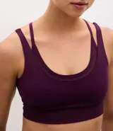 Top deportivo de microfibra color violeta con diseño de doble bretel y detalle de superposición con tul en el escote. Incluye copas removibles para mayor soporte.