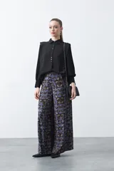 Camisa negra de estilo sastrero con cuello clásico, frente abotonado y mangas largas con puños ajustados. Presenta un diseño con hombreras sutiles que aportan estructura a la prenda.