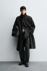 Trench de corte oversized confeccionado en tejido compacto con mezcla de lana. Presenta cuello solapa, cierre frontal con botonadura, mangas largas y bolsillos de vivo en la cadera.