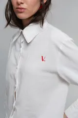 Camisa de corte holgado confeccionada en algodón tussor, con cuello clásico de tamaño ligeramente ampliado, mangas largas con pinzas laterales y puños anchos. Presenta pespuntes en color rojo a contraste y logo bordado en el pecho.
