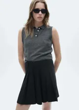 Falda corta de tablas con diseño evasé y estampado de raya diplomática. Cuenta con trabillas en la cintura y cierre de cremallera invisible en la parte posterior.