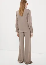 Pantalón plisado de corte ancho en color beige con sutiles rayas verticales, de tiro medio con cintura elástica.