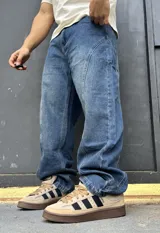 Pantalón de denim azul con diseño balloon y costuras curvas decorativas en las piernas.